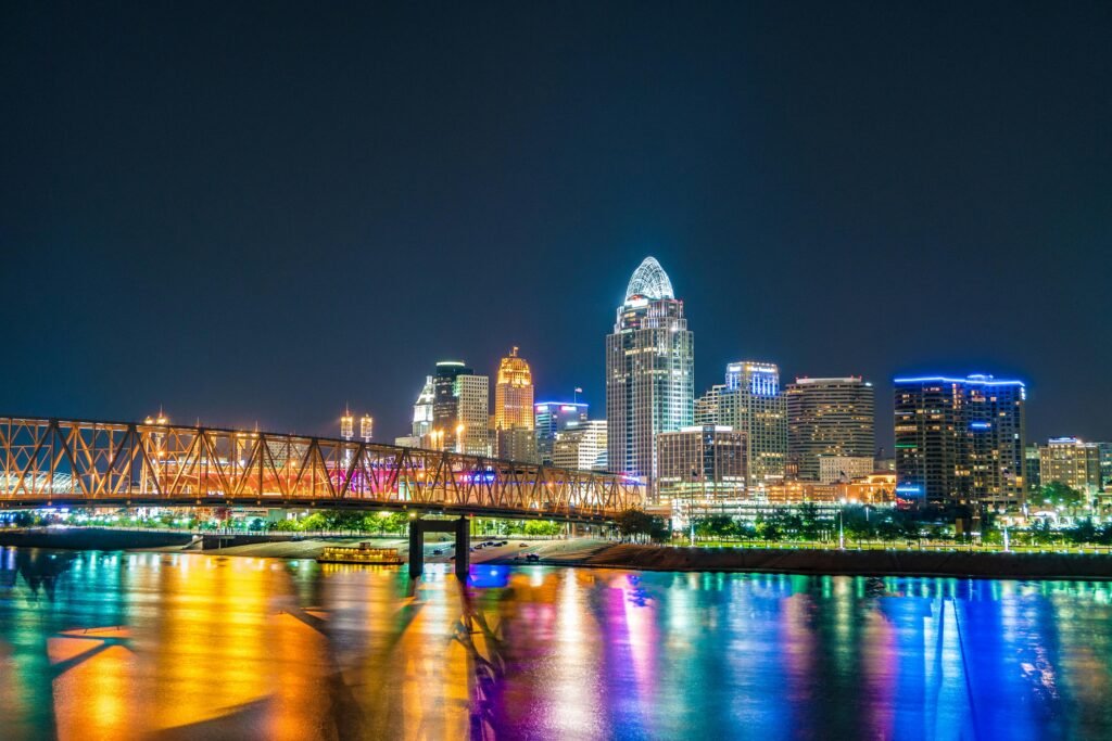 Captivating view of Cincinnati skyline with bridge reflections on Ohio River at night.